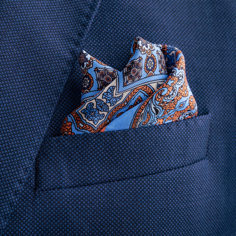 'Millefiori' silk pocket square in mid blue with orange by Otway & Orford folded in top pocket